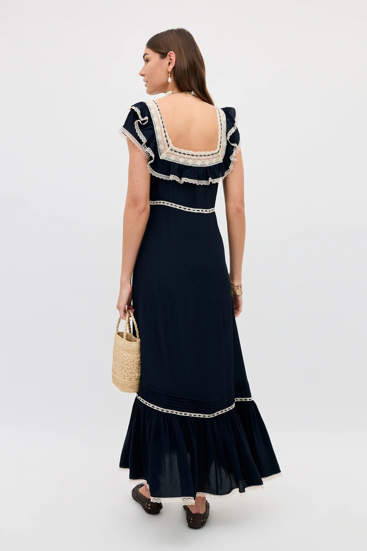 Woman wearing a navy dress with white lace details on a white background
