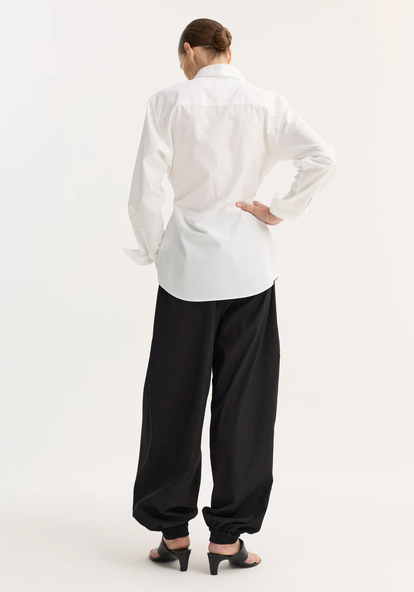 Person wearing a white shirt and black pants on a white background