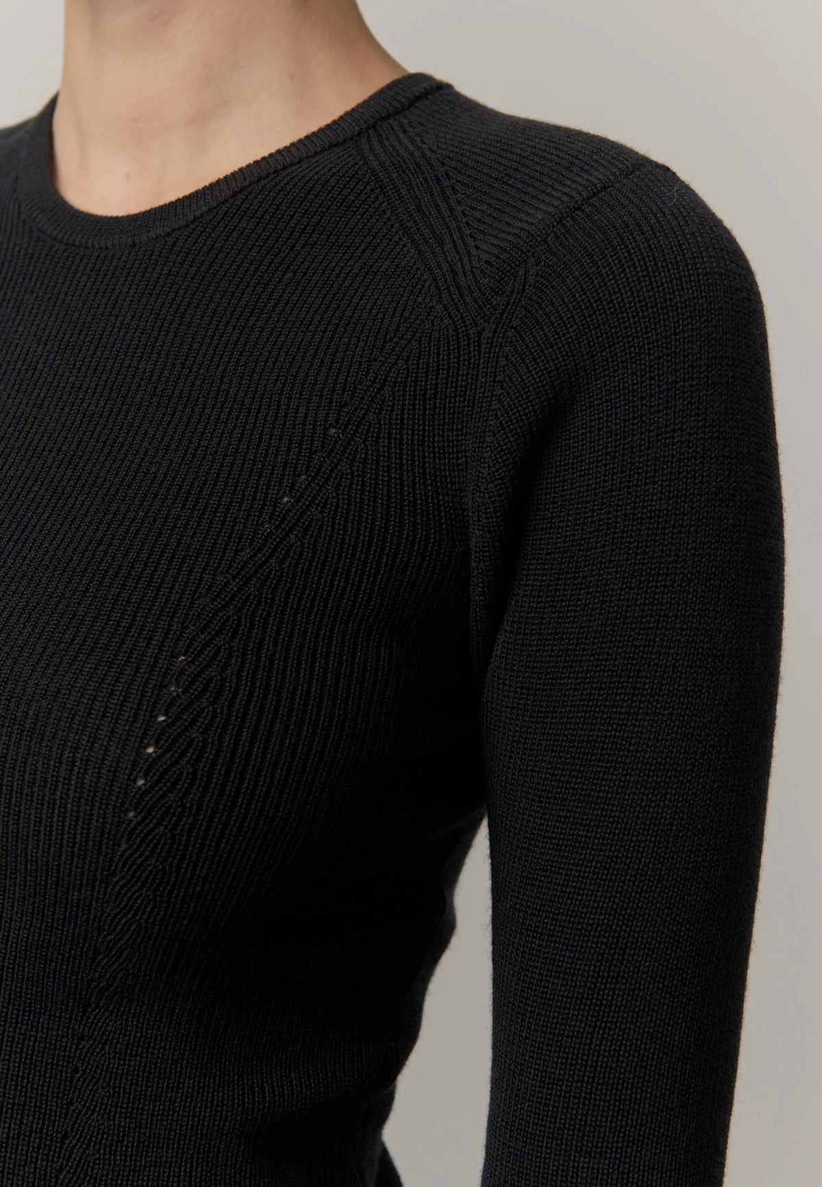 Black ribbed sweater on a neutral background