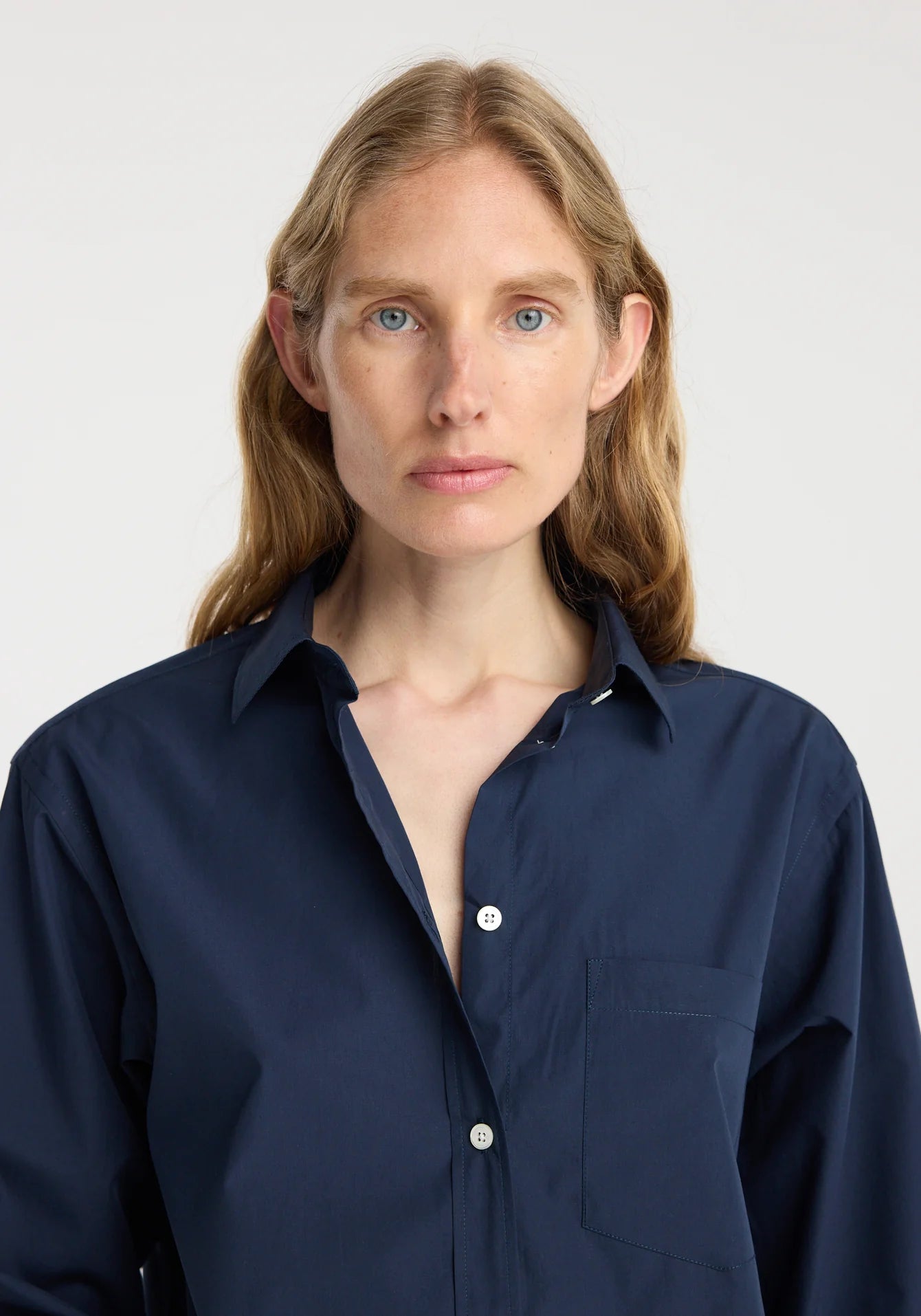 Woman wearing a navy blue shirt against a plain background