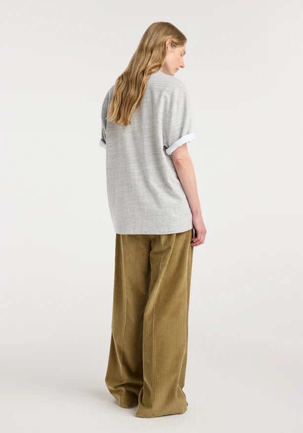 Person wearing a light gray sweater and beige pants on a white background