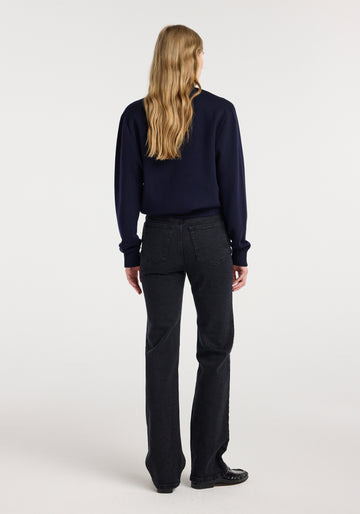 Person wearing a navy shirt and black pants on a white background