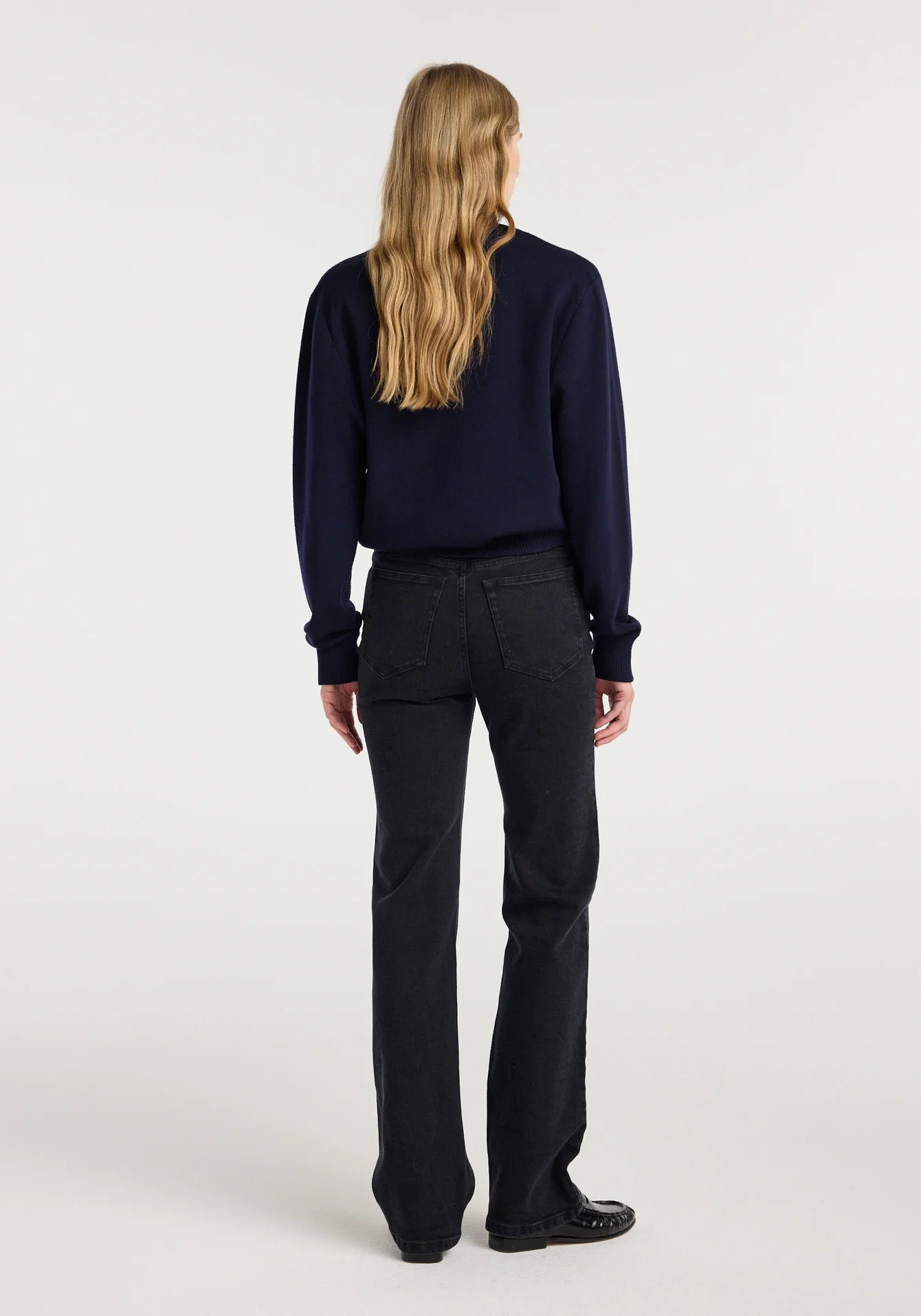 Person wearing a navy shirt and black pants on a white background