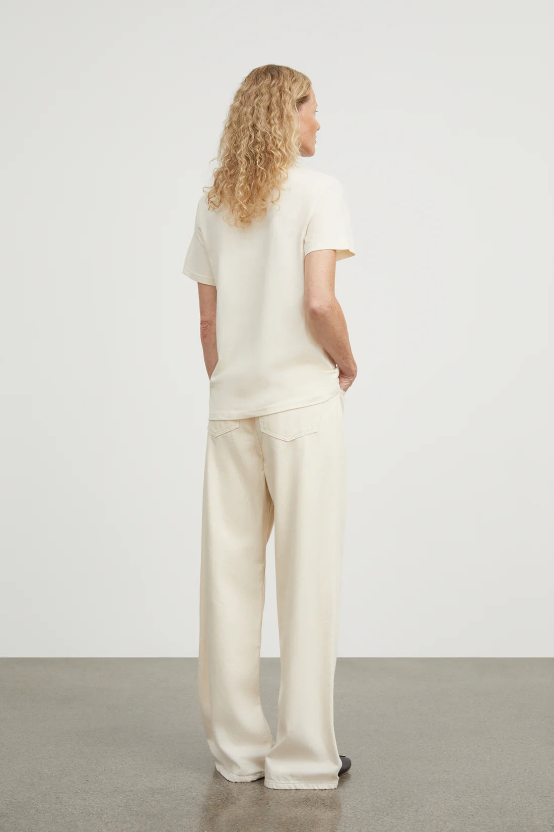 Person wearing a white outfit standing against a plain background