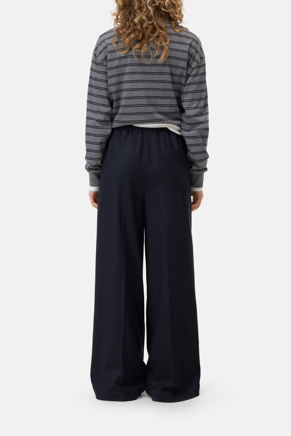 Person wearing a striped sweater and wide-leg pants on a white background