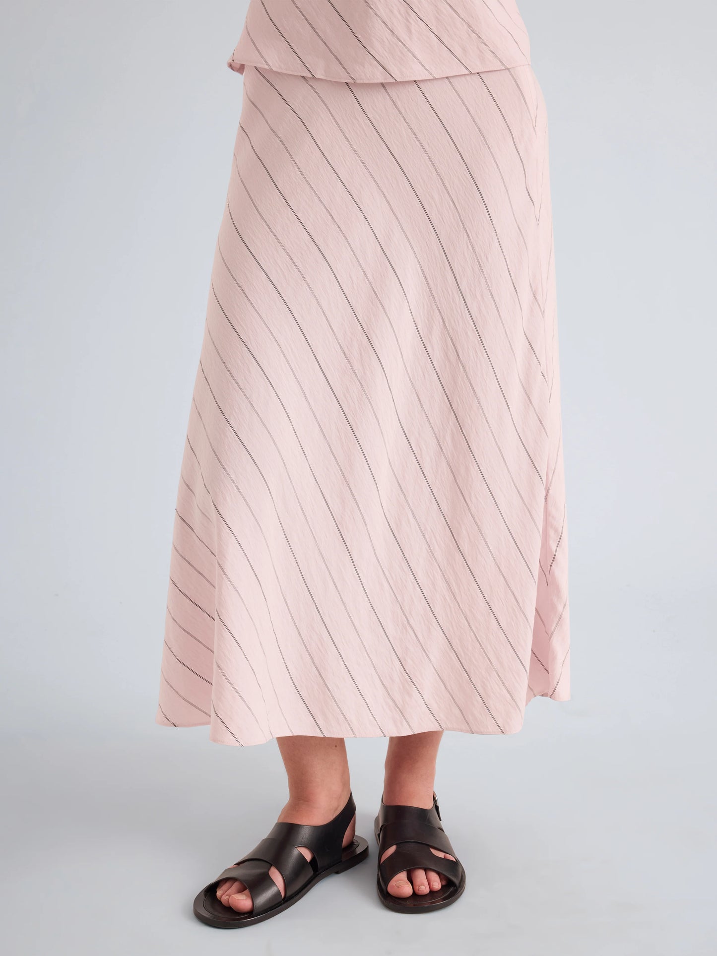 Person wearing a pink striped skirt on a light gray background