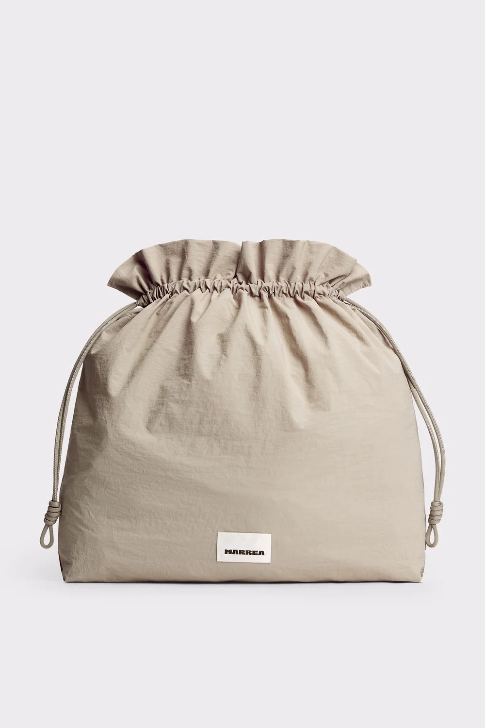 A beige drawstring pouch with a gathered top and a small white rectangular label reading 'MINEGA' near the bottom front, photographed on a light gray background.