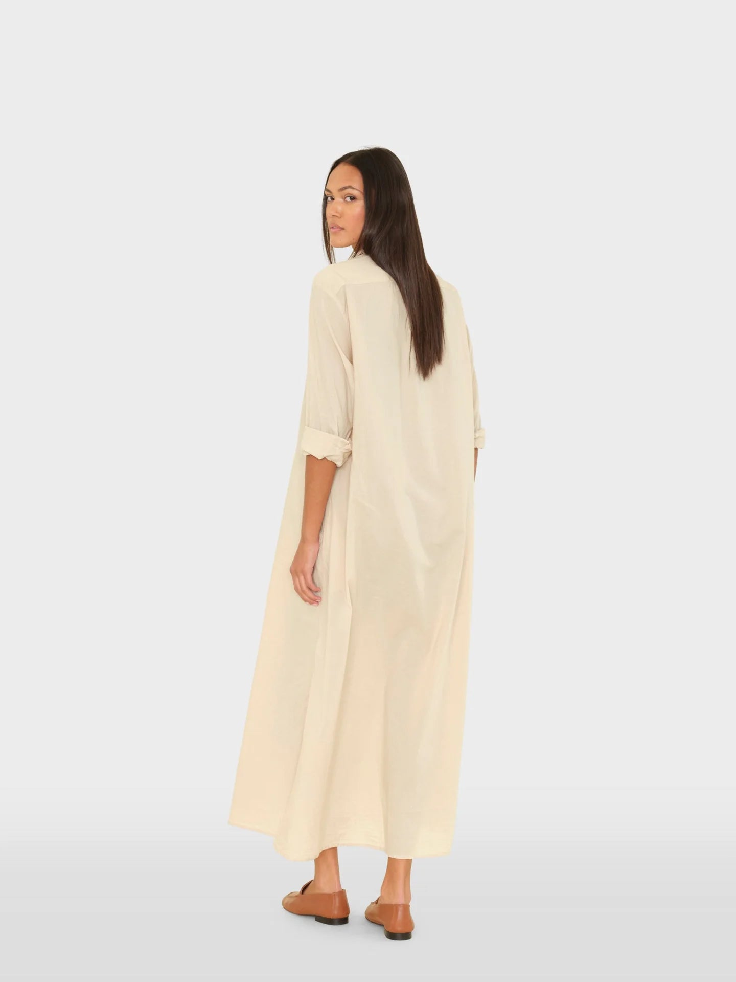 Woman wearing a long beige dress on a white background