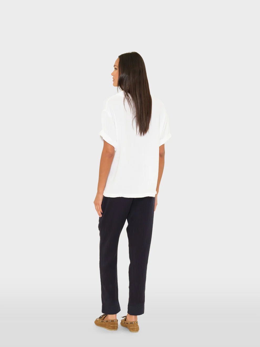Person wearing a white shirt and dark pants on a white background