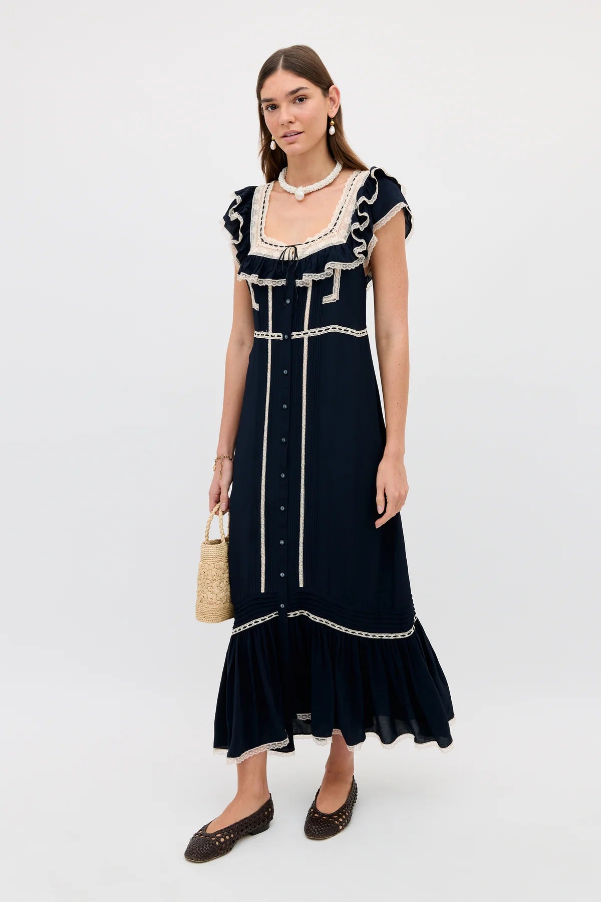 Woman wearing a navy dress with white trim on a white background