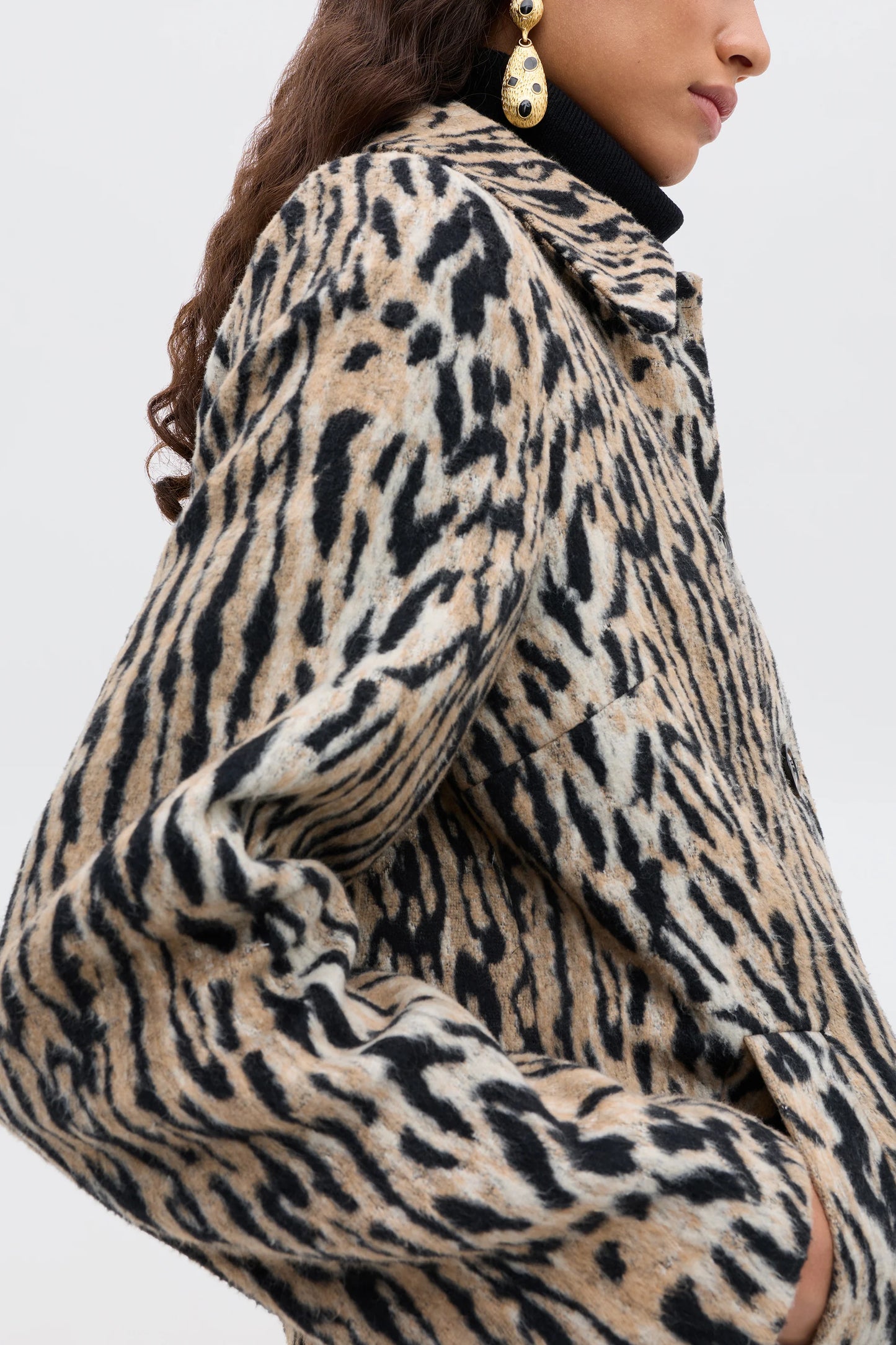 Leopard print coat worn by a person on a plain background