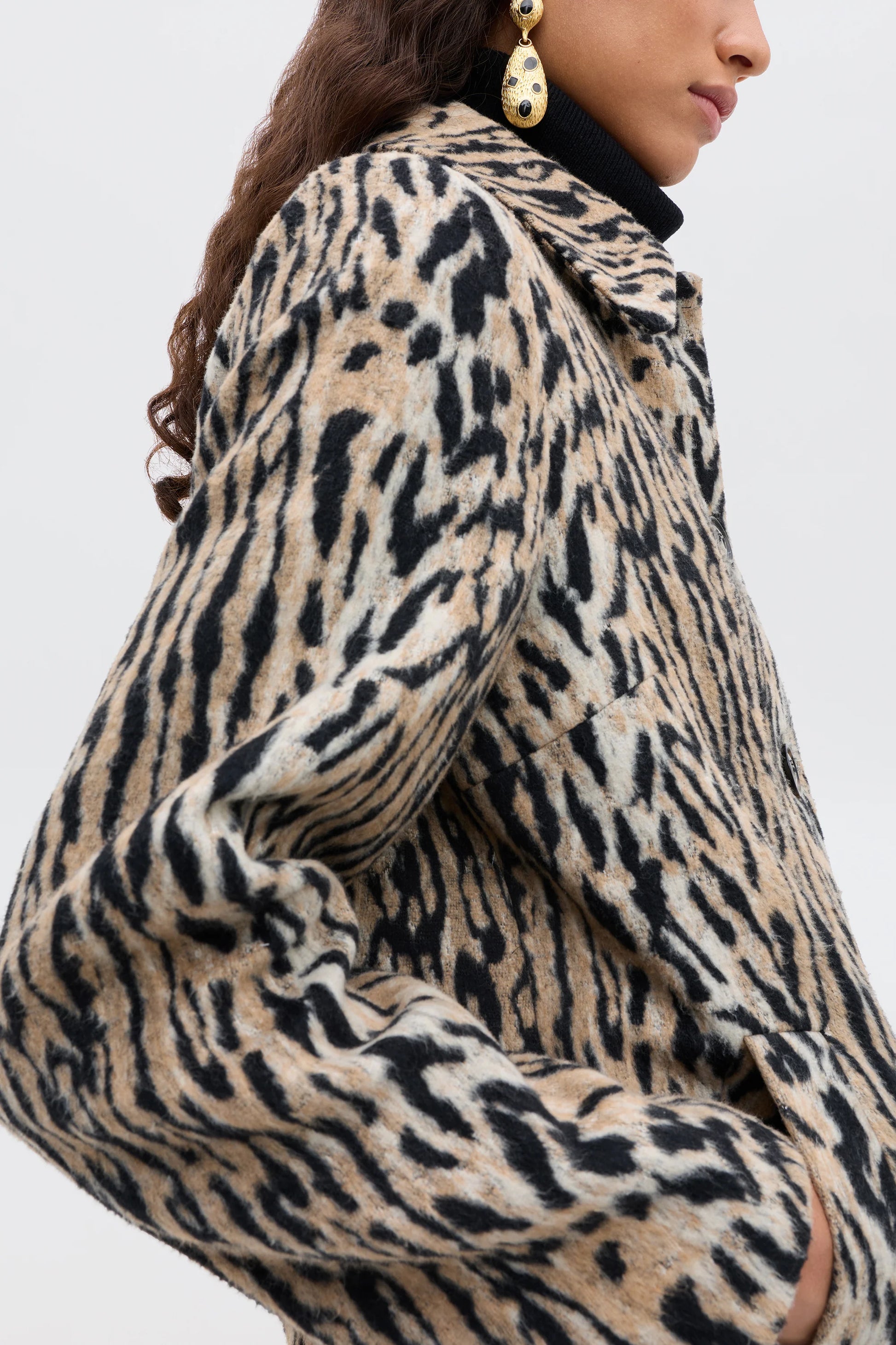 Leopard print coat worn by a person on a plain background