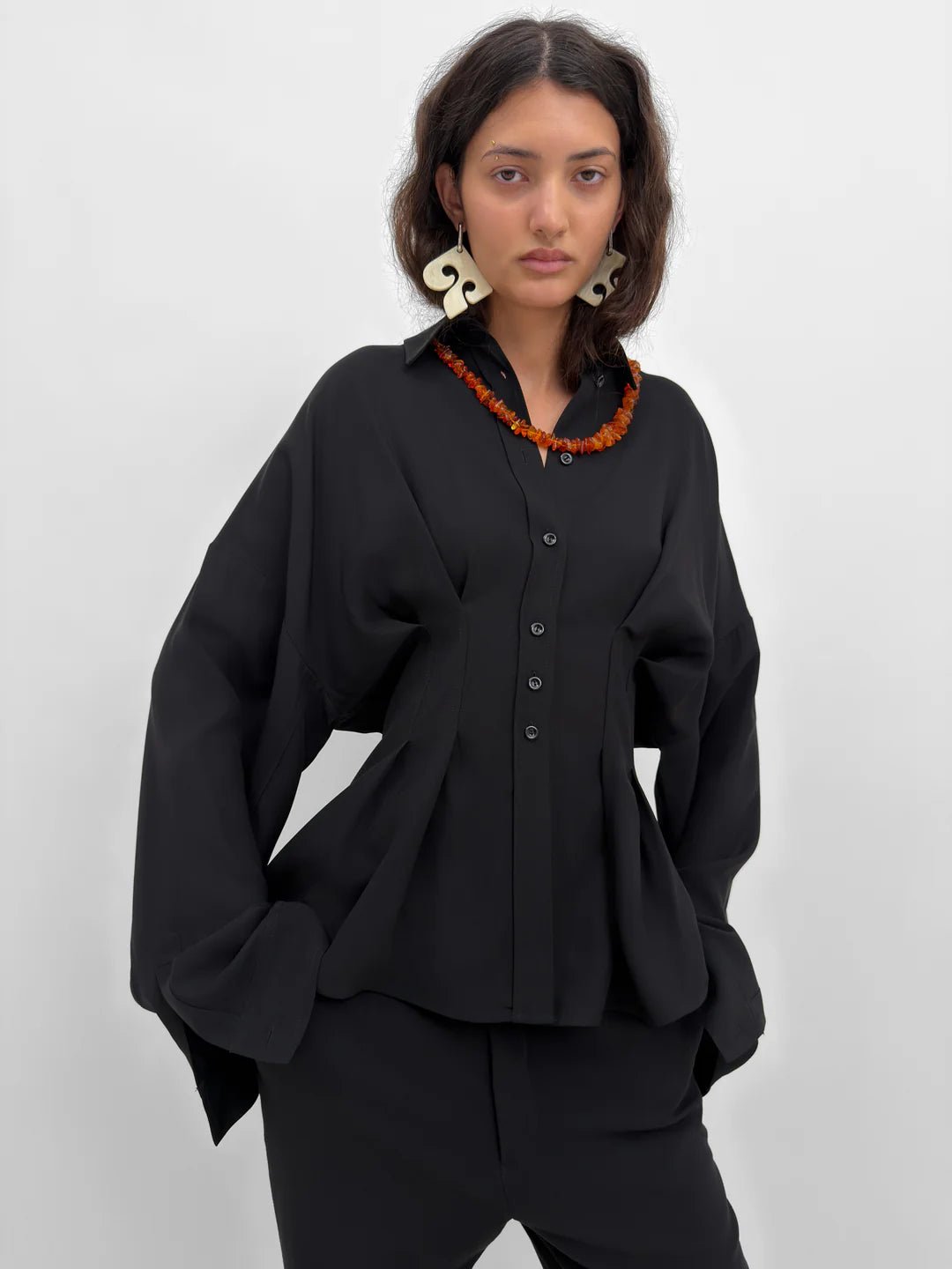 Woman wearing a black outfit with a textured collar against a white background