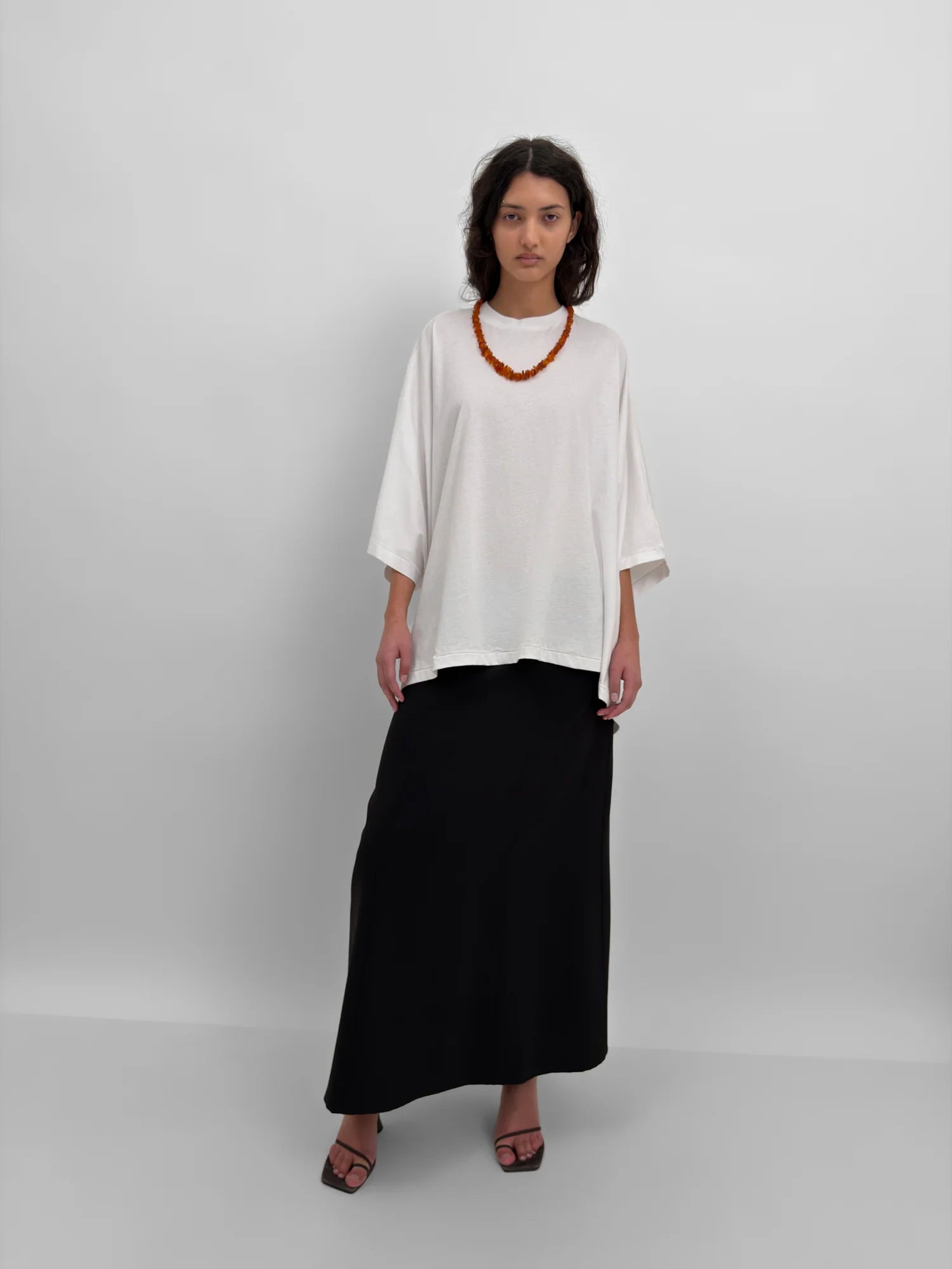 Person wearing a white top and black skirt on a plain background
