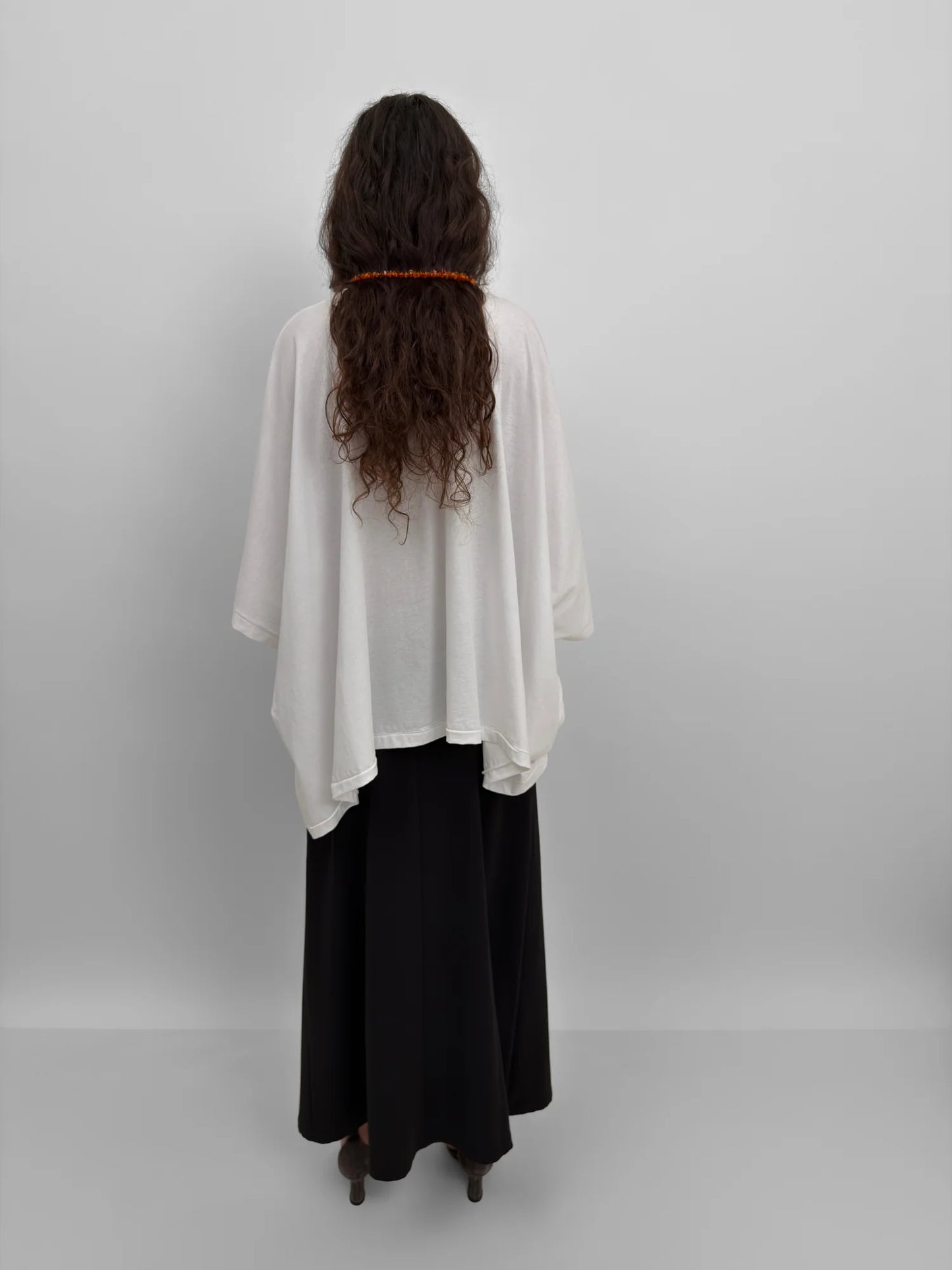 Person wearing a white top and black pants against a plain background
