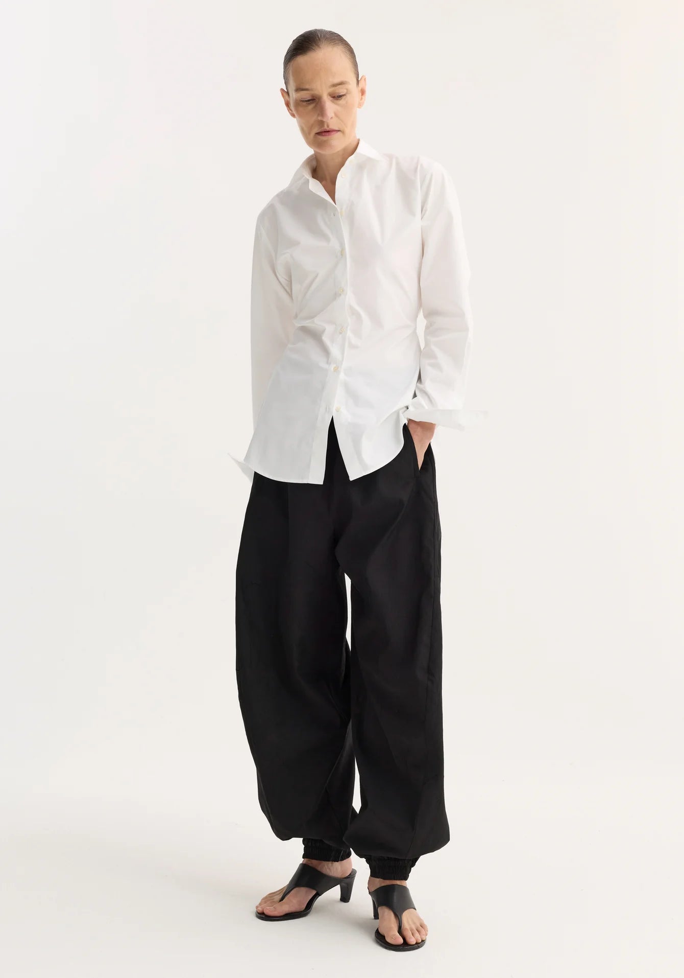 Person wearing a white shirt and black pants on a white background