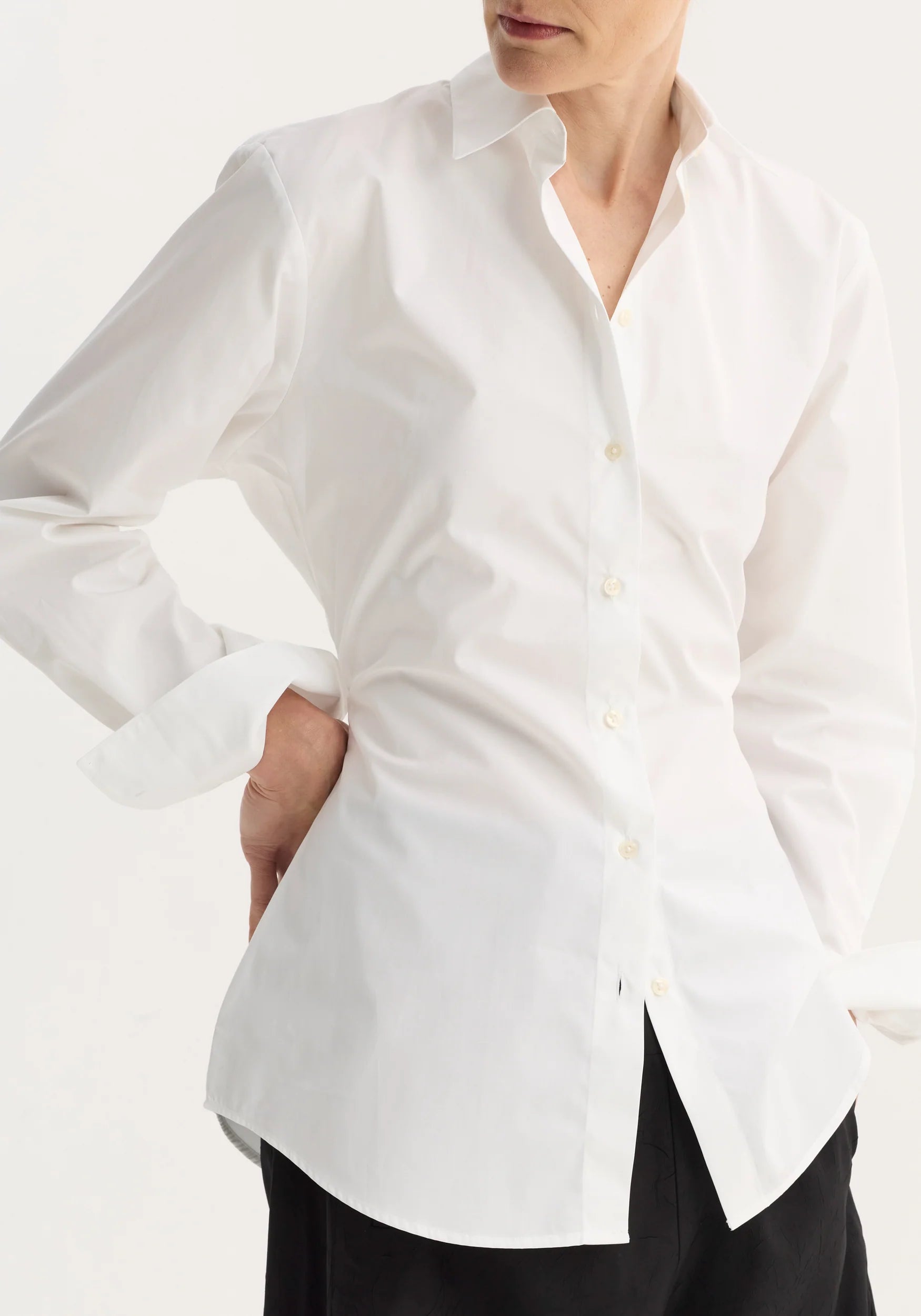 Person wearing a white shirt with a plain background