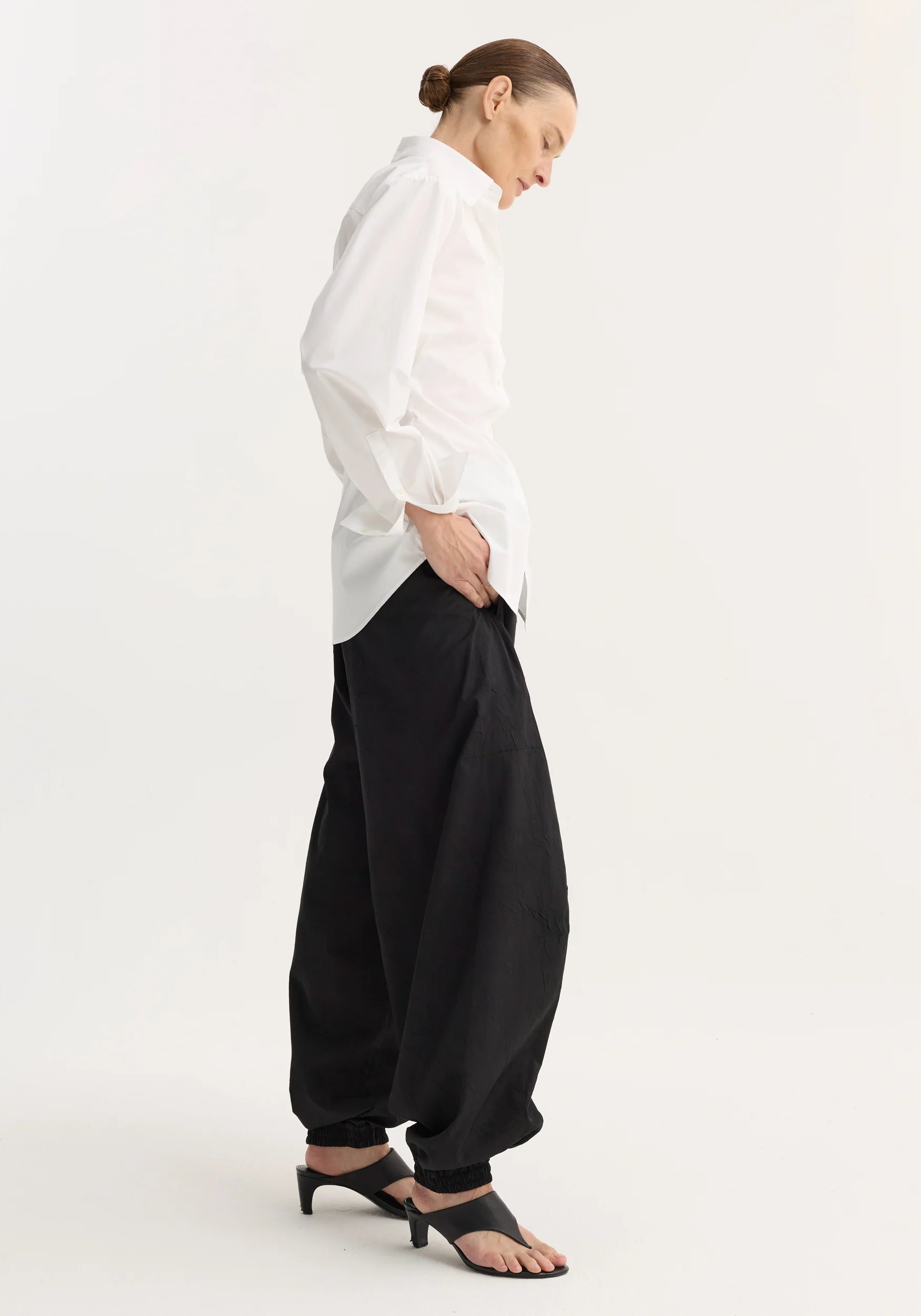 Person wearing a white shirt and black pants on a white background