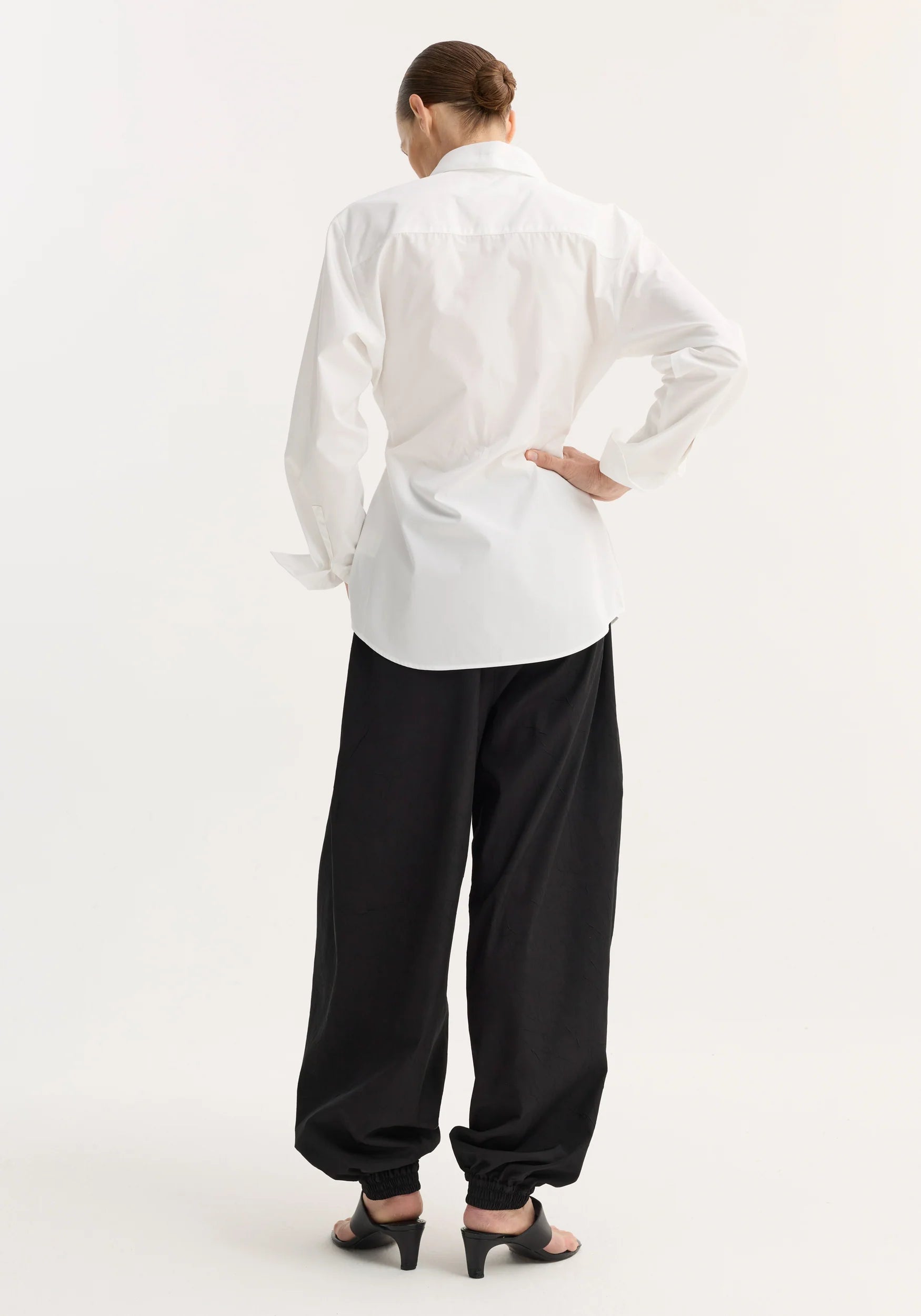 Person wearing a white shirt and black pants on a white background