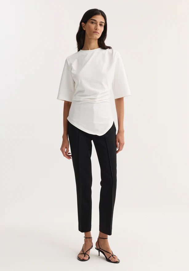 Woman wearing a white blouse and black pants on a white background