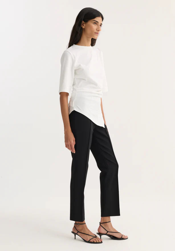 Woman wearing a white top and black pants on a white background