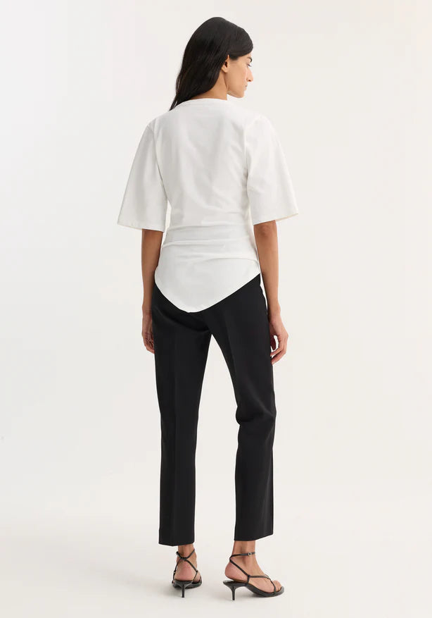 Woman wearing a white blouse and black pants on a white background