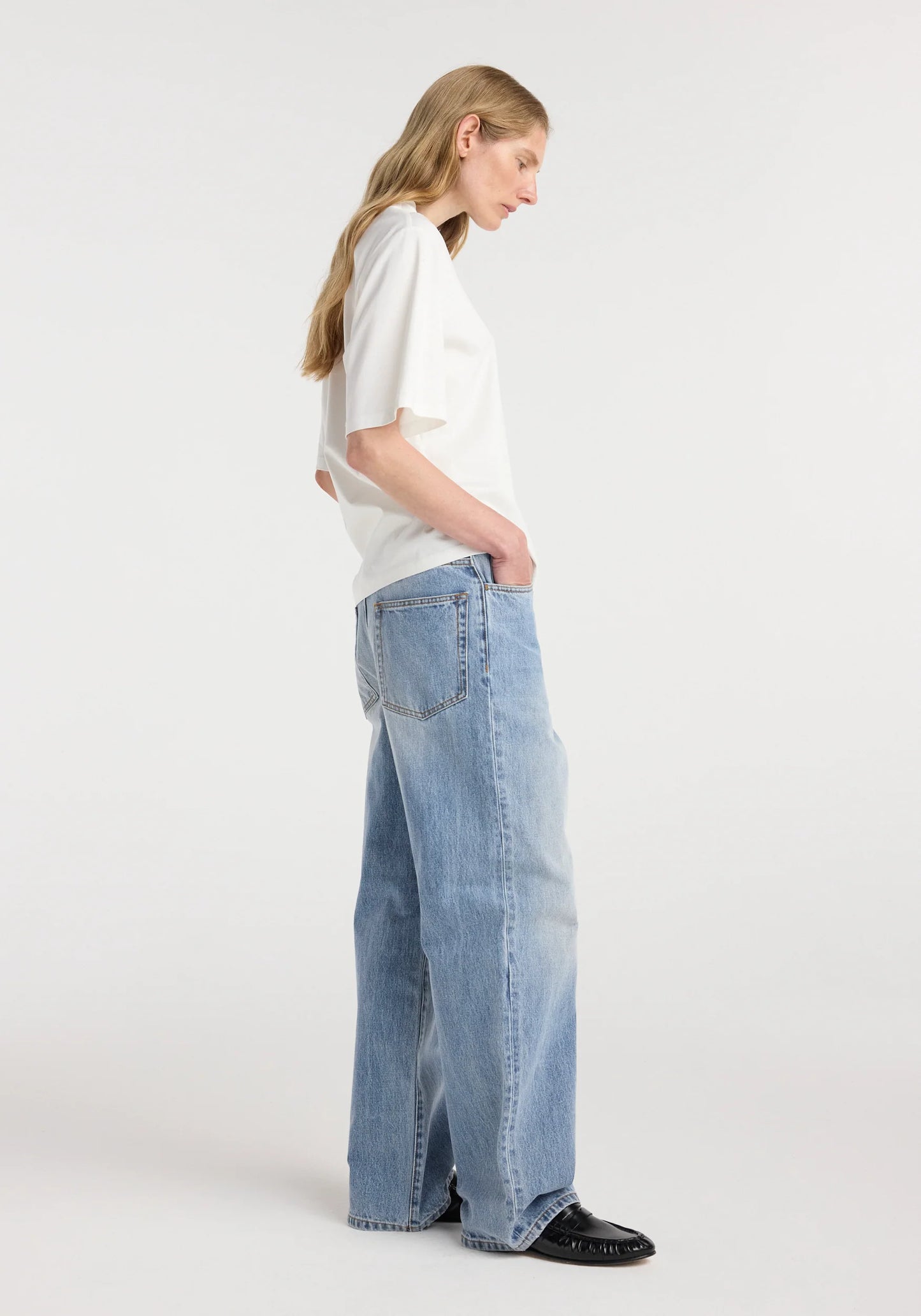 Woman wearing a white t-shirt and light blue jeans on a white background