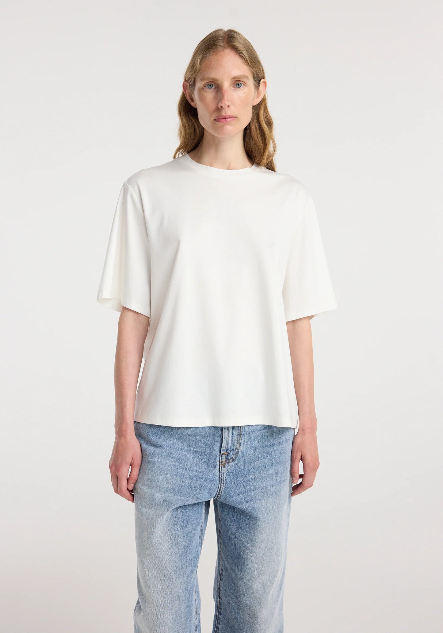 Woman wearing a white t-shirt and light blue jeans on a white background