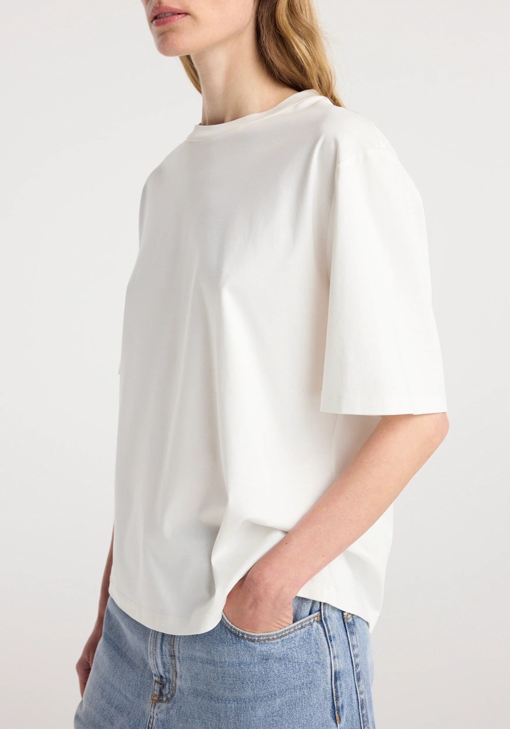 Person wearing a white t-shirt and blue jeans on a plain background
