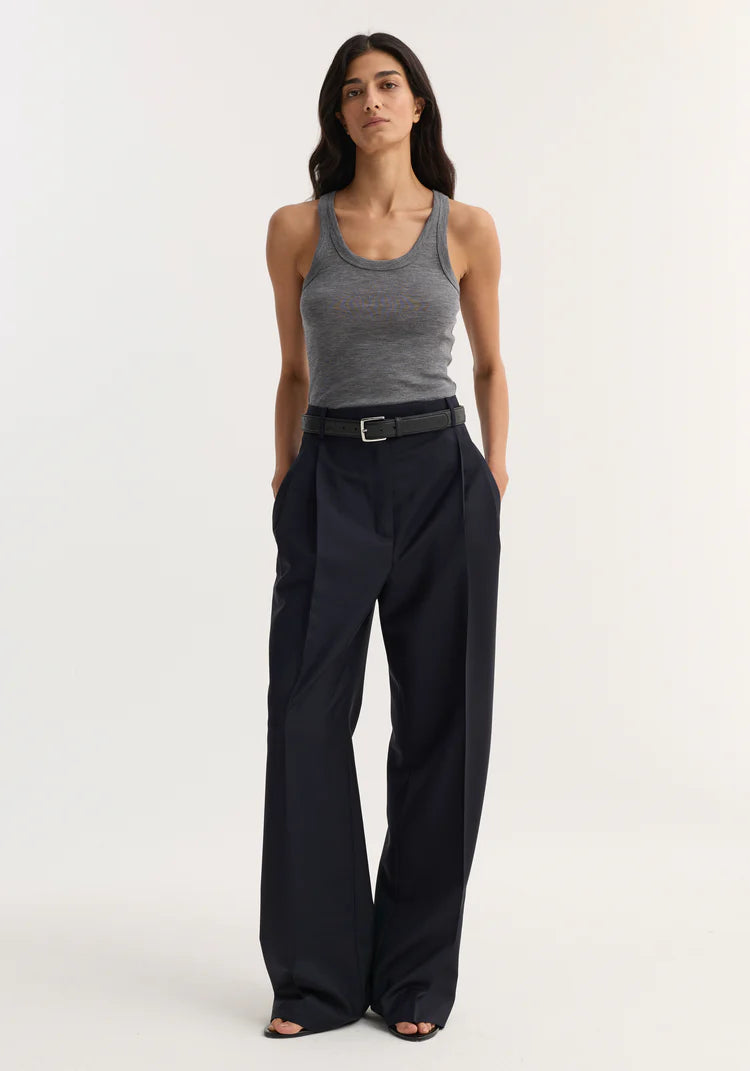 Woman wearing a gray tank top and black wide-leg pants on a white background