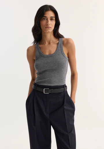 Woman wearing a gray tank top and black pants on a white background