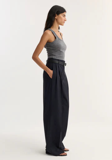 Woman wearing a gray tank top and black wide-leg pants on a white background