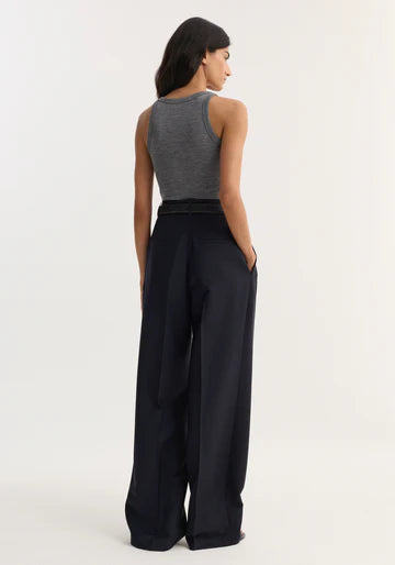 Woman wearing a gray tank top and black wide-leg pants on a white background
