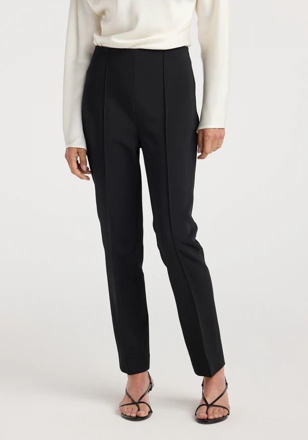 Person wearing black pants and a white top on a white background