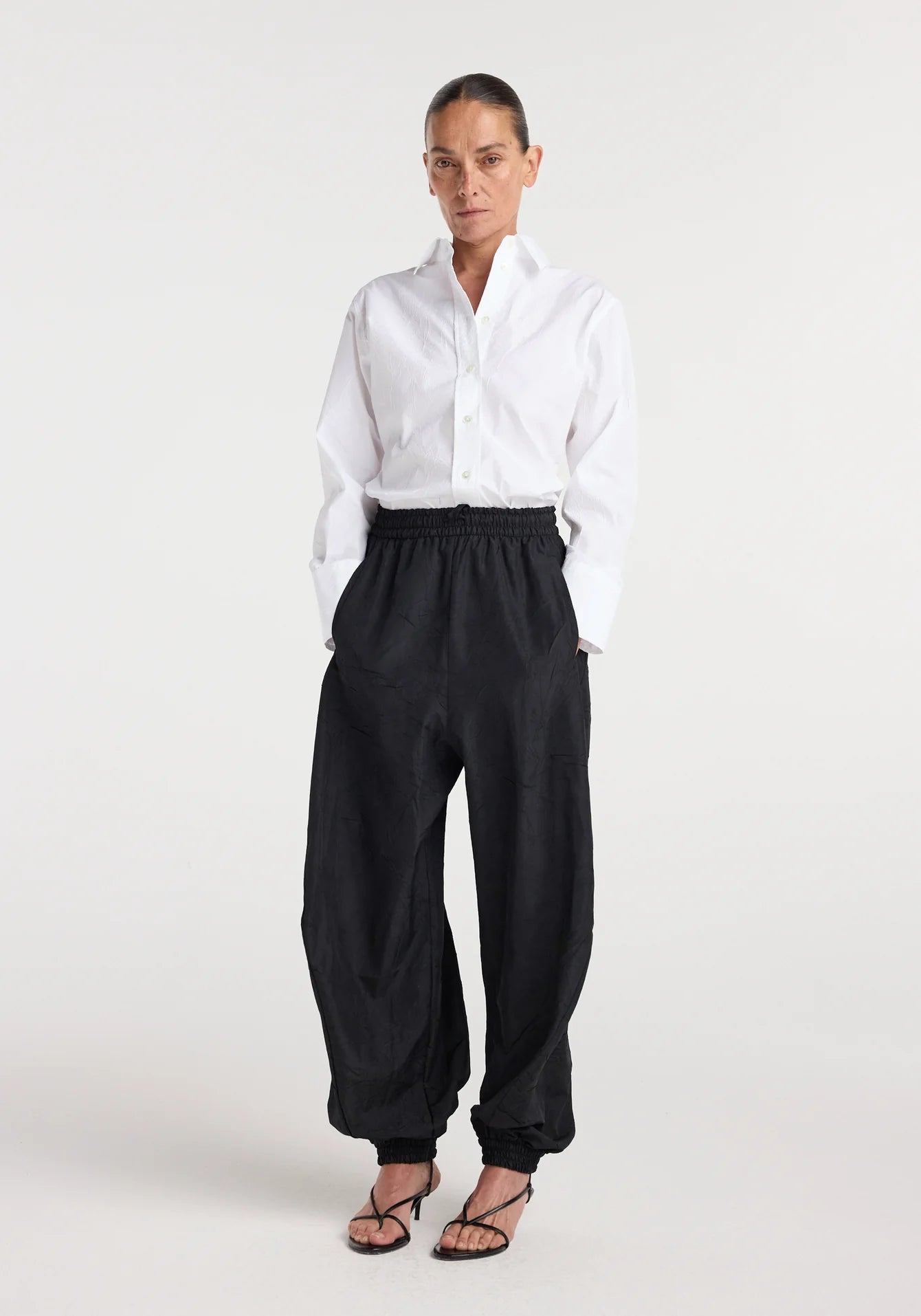 Person wearing a white shirt and black pants on a white background