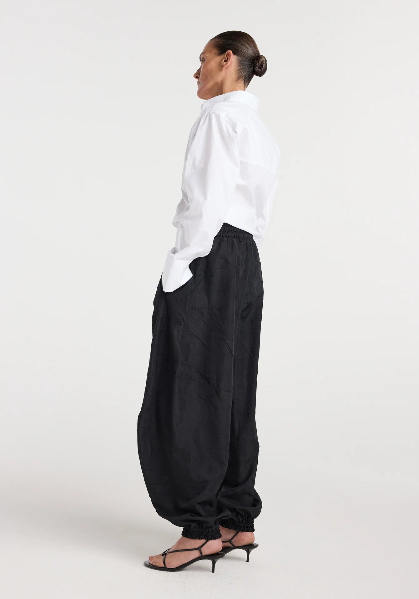 Person wearing a white shirt and black pants on a white background