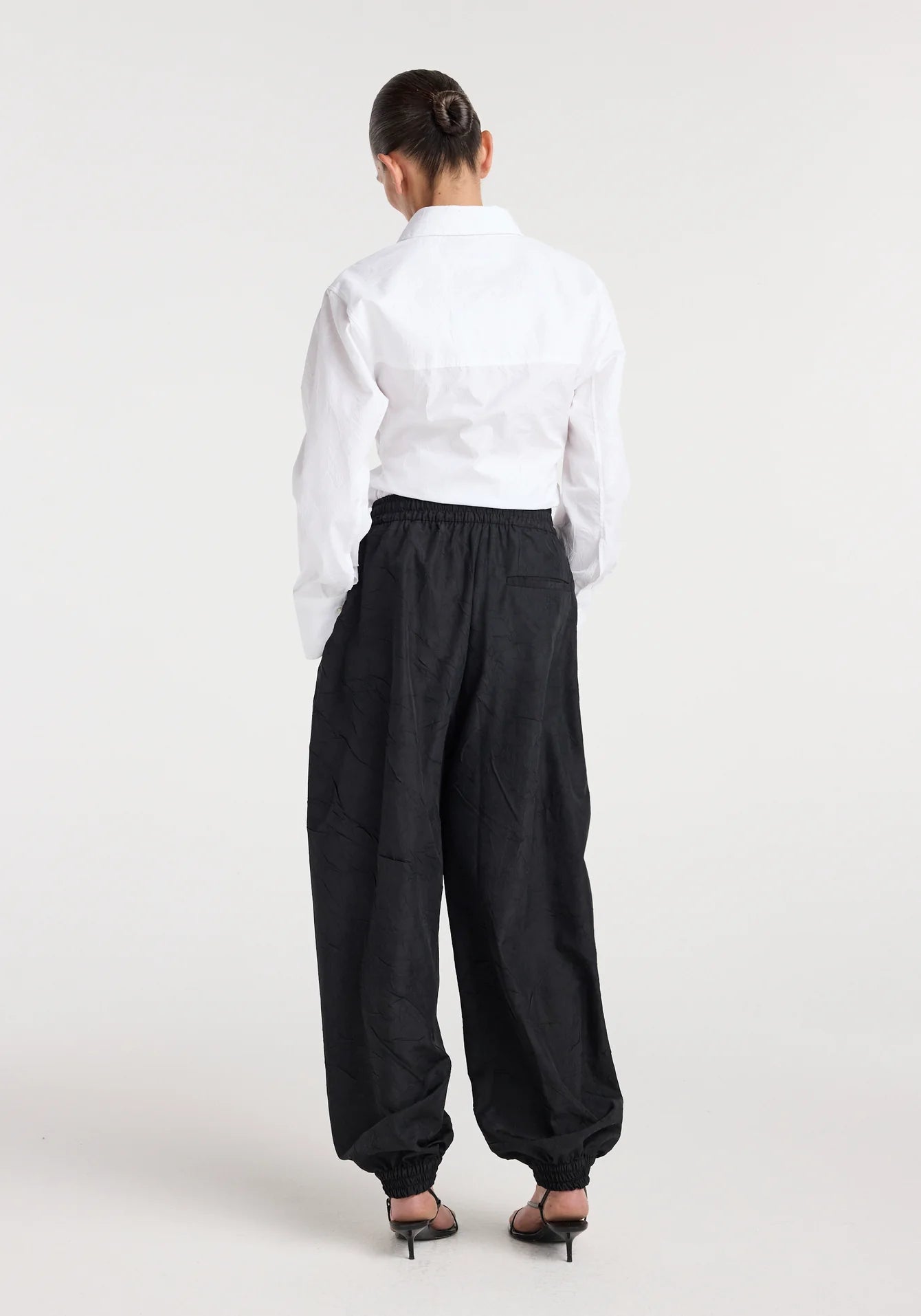 Person wearing a white shirt and black pants on a white background