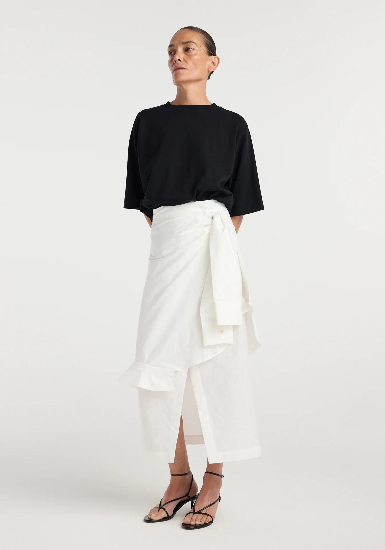 Woman wearing a black top and white skirt on a white background