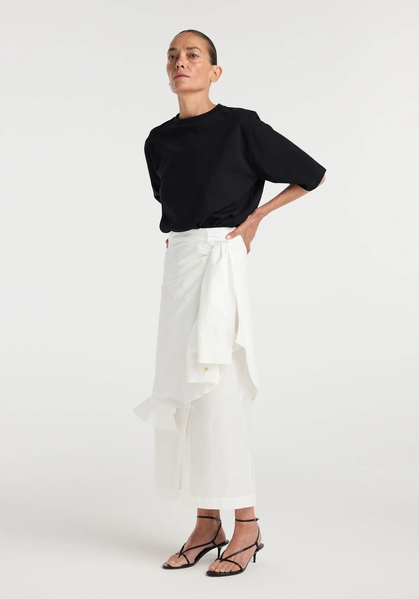 Person wearing a black top and white pants on a white background