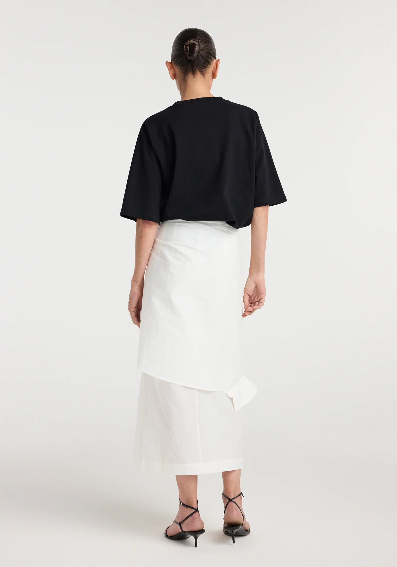 Person wearing a black top and white skirt on a white background