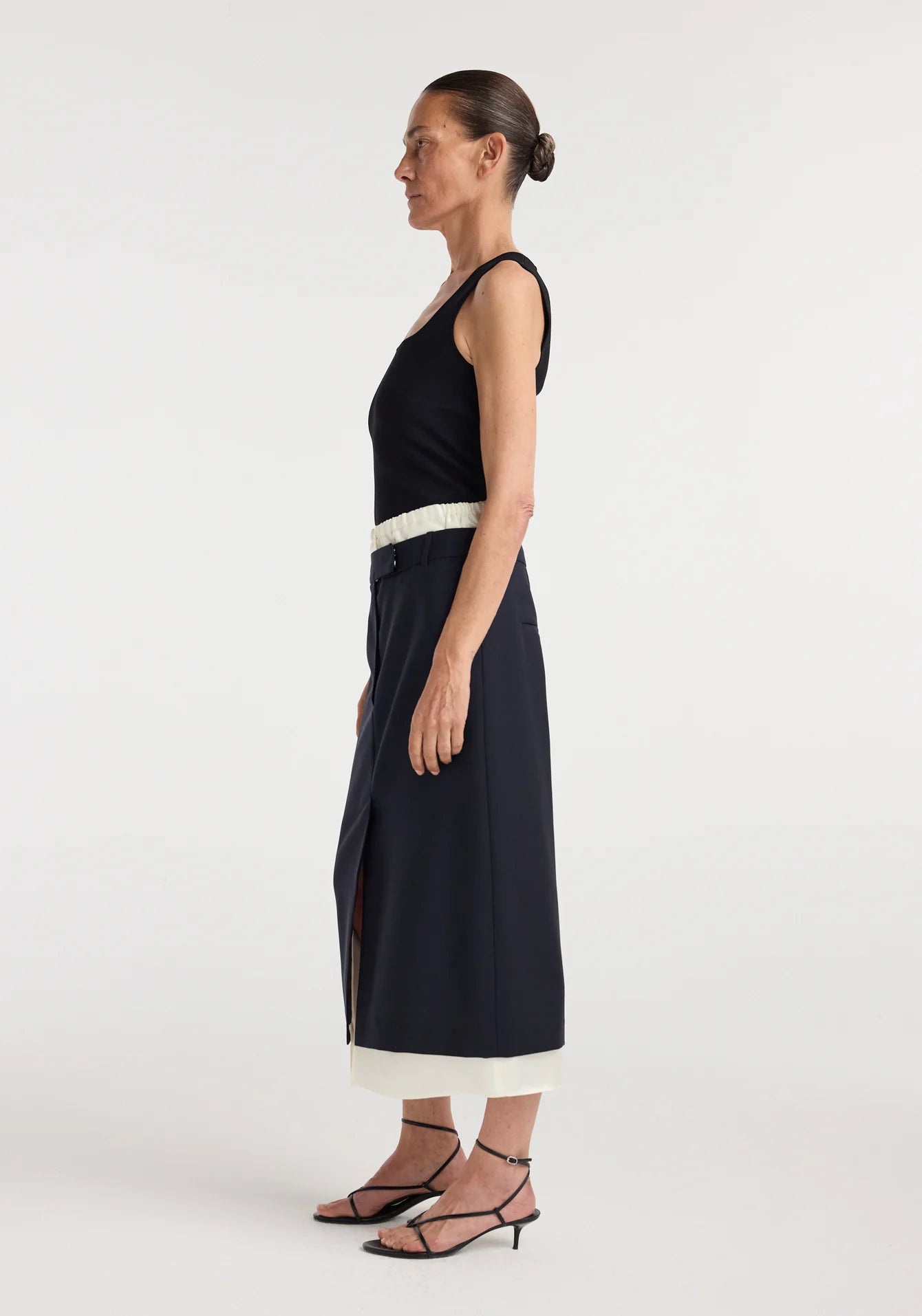 Woman wearing a black dress with a white belt on a white background