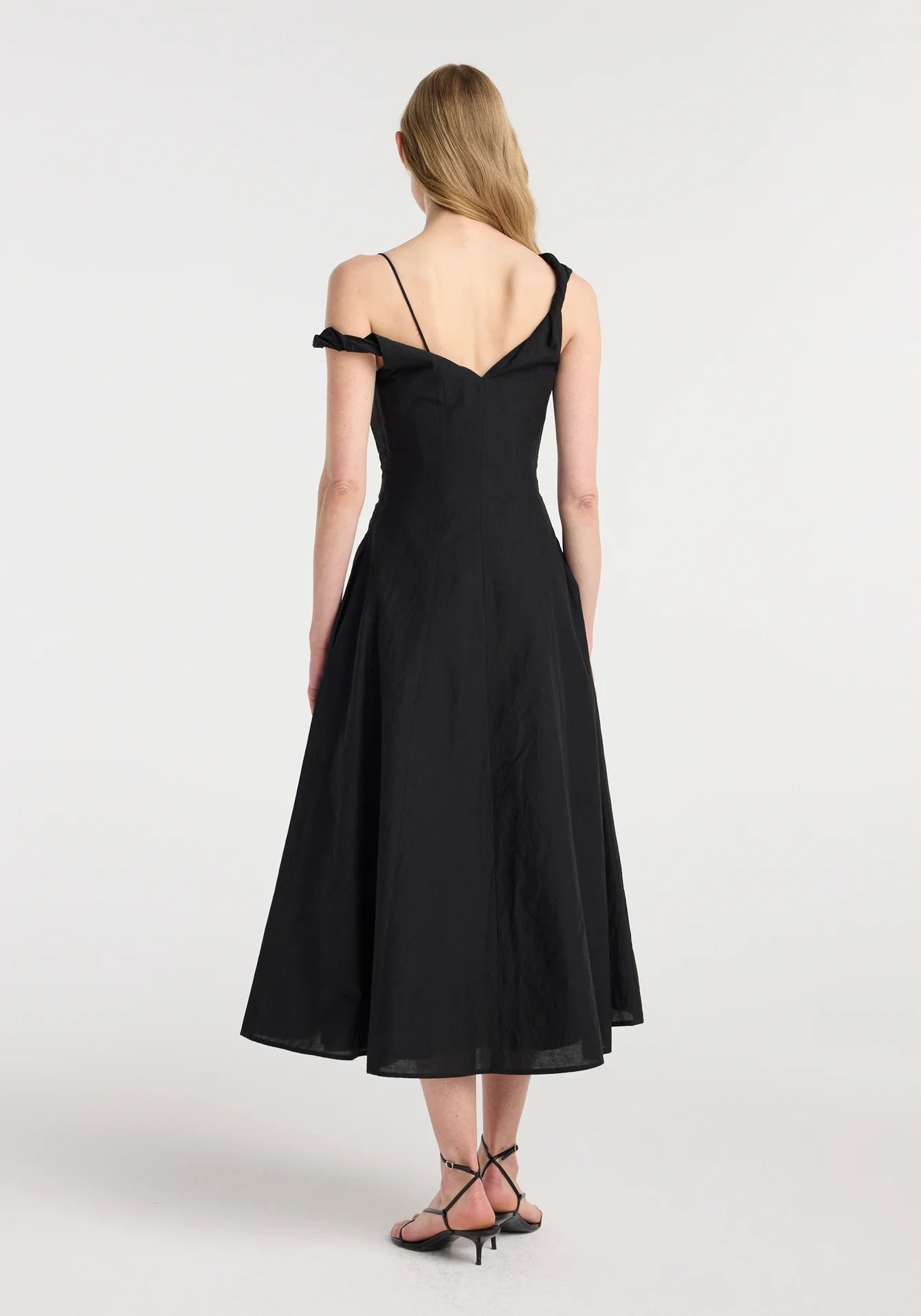 Back view showcasing the asymmetric open back and twisted shoulder construction.