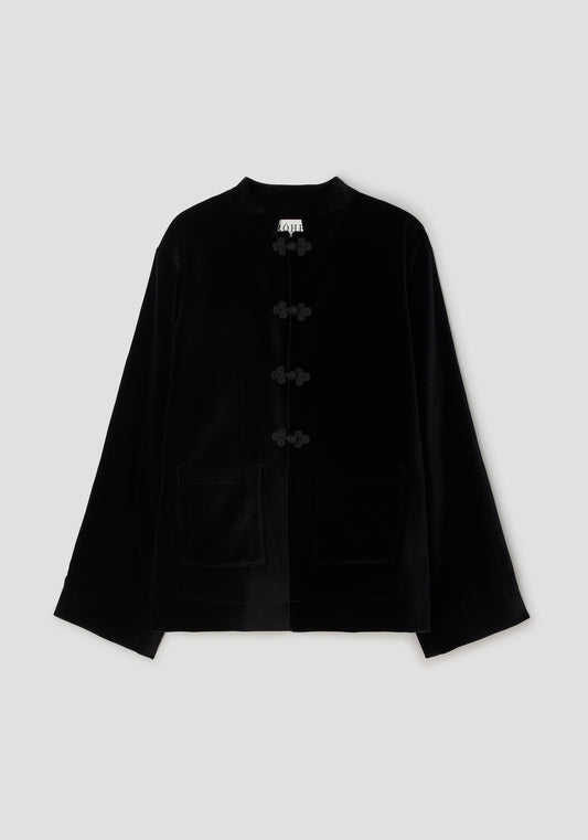 A black velvet long-sleeve jacket with traditional Chinese-style frog closures on the front and two front patch pockets, displayed against a neutral light gray background.