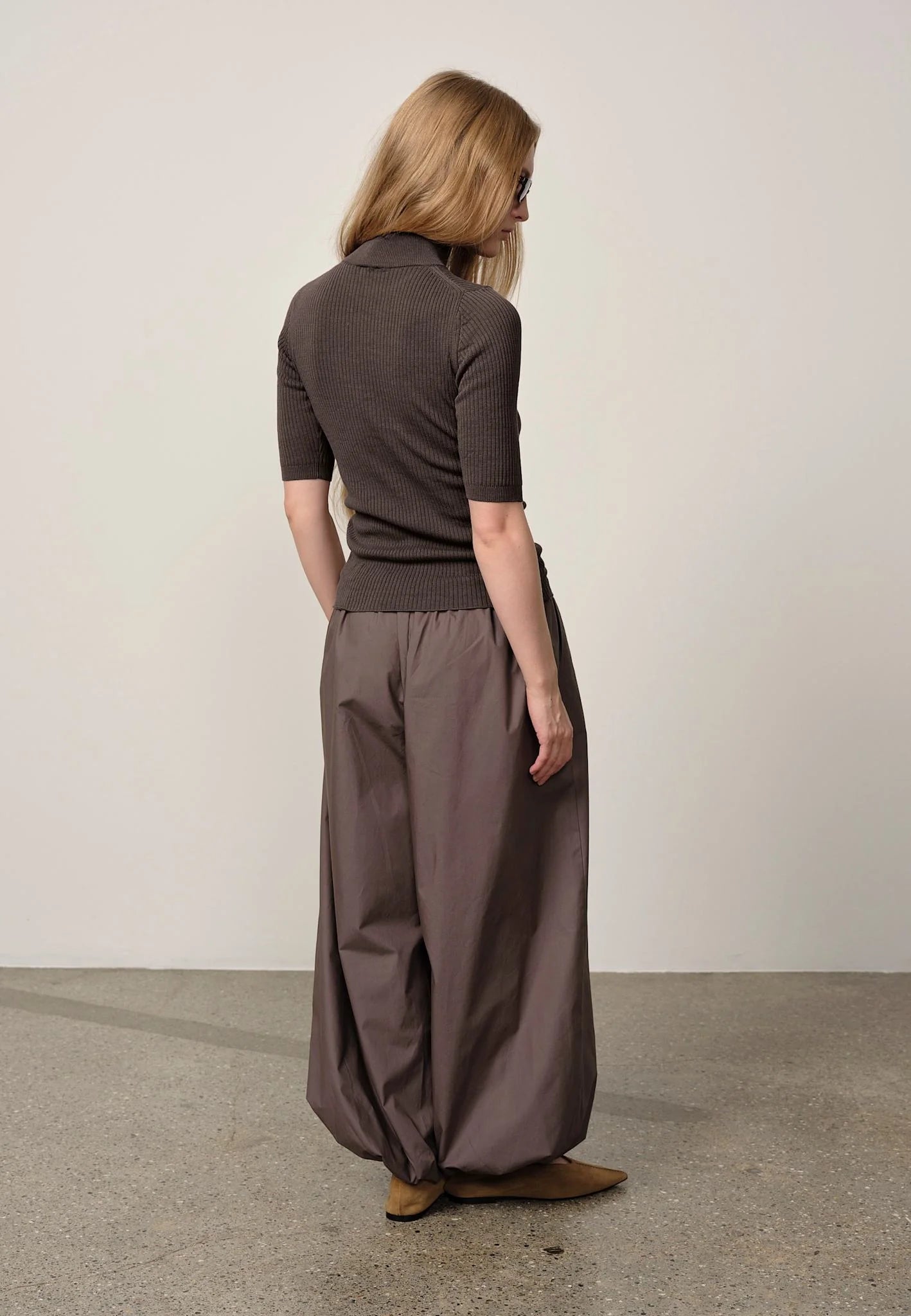Person wearing a brown outfit standing against a plain background
