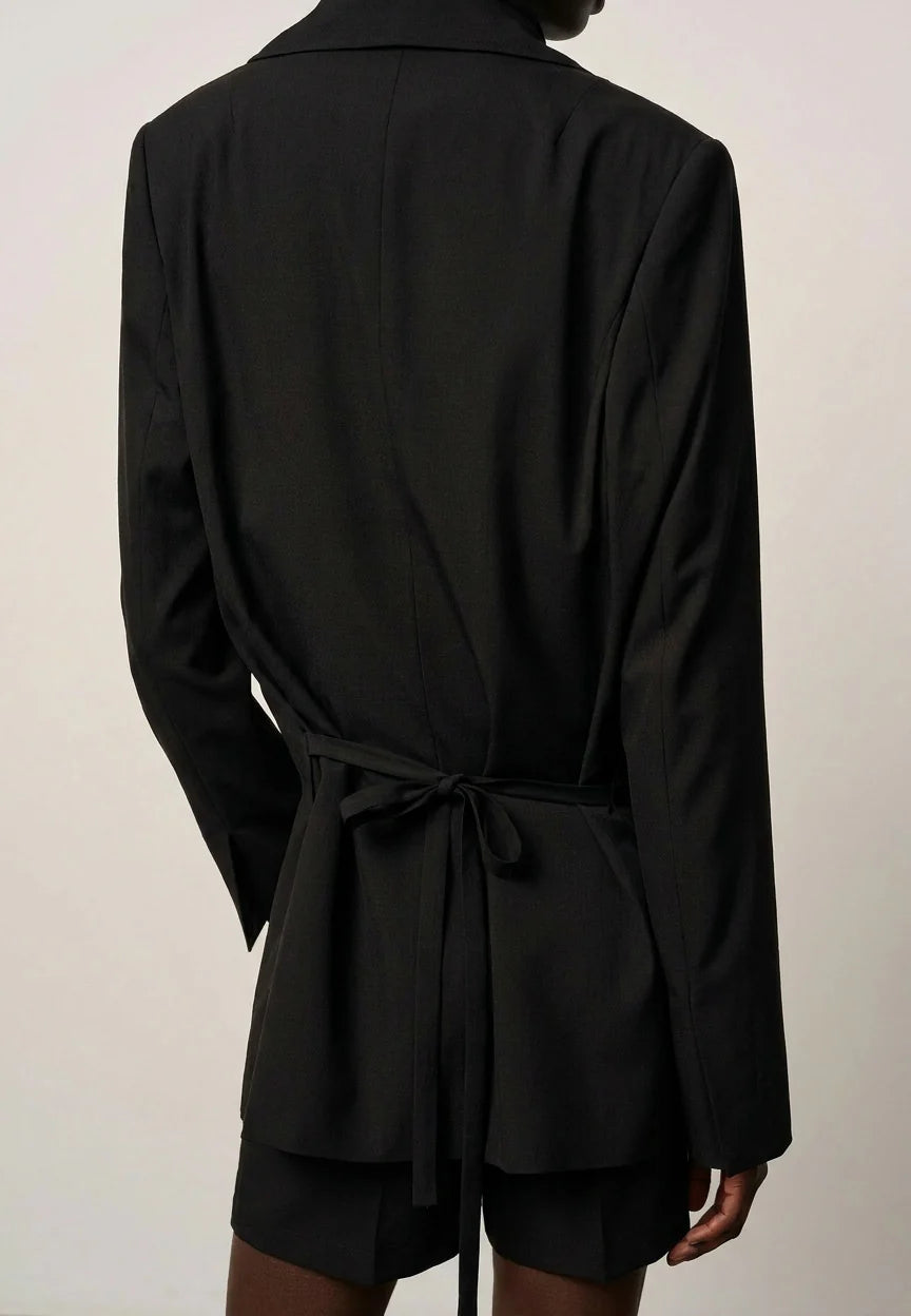 Black blazer with a tie waist on a plain background