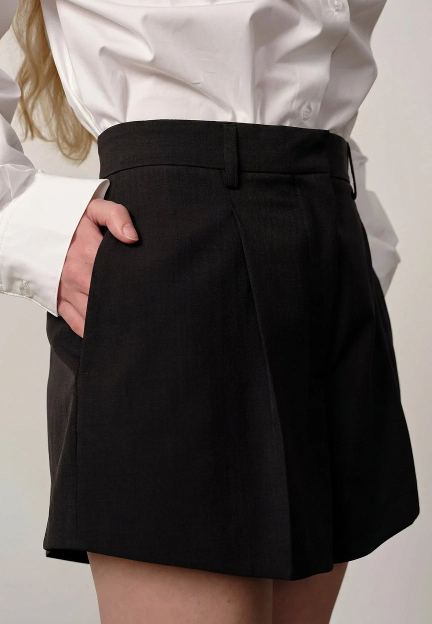 Person wearing a black skirt with a white shirt on a plain background