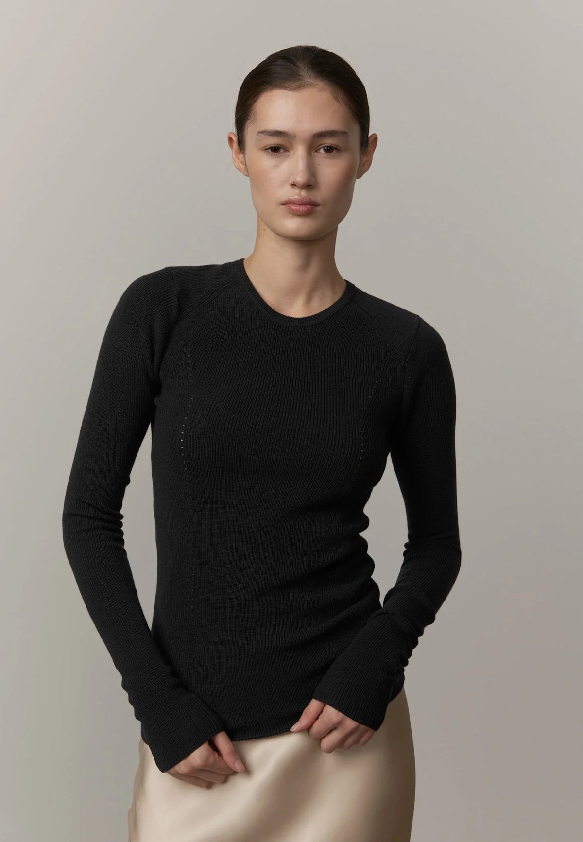 Person wearing a black long-sleeve top against a plain background