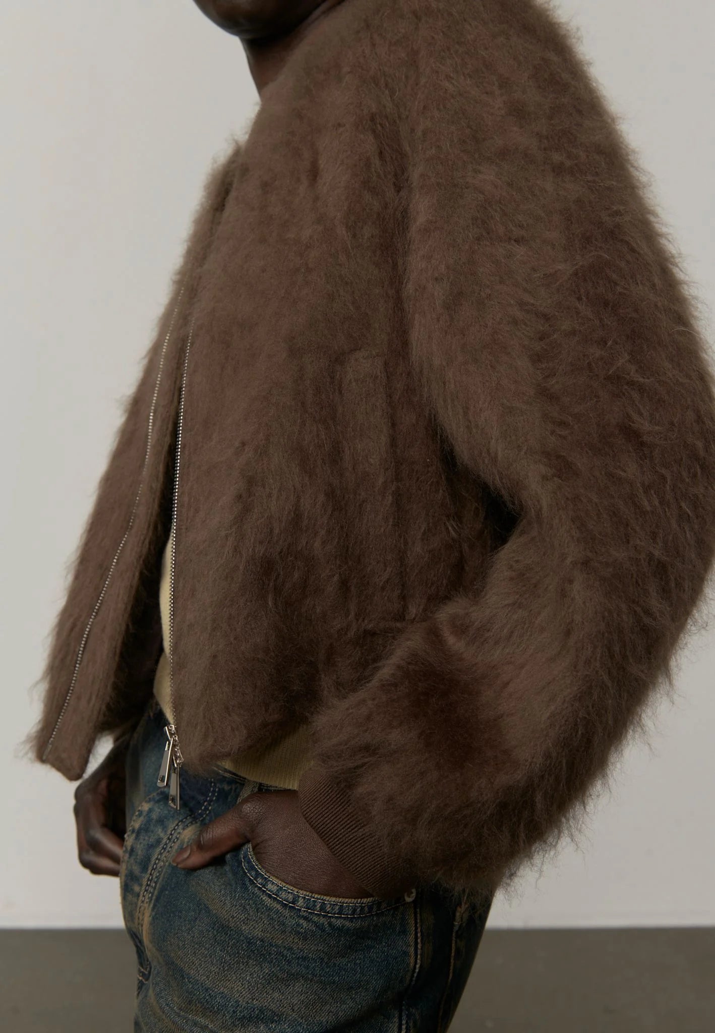 Person wearing a brown textured jacket against a plain background