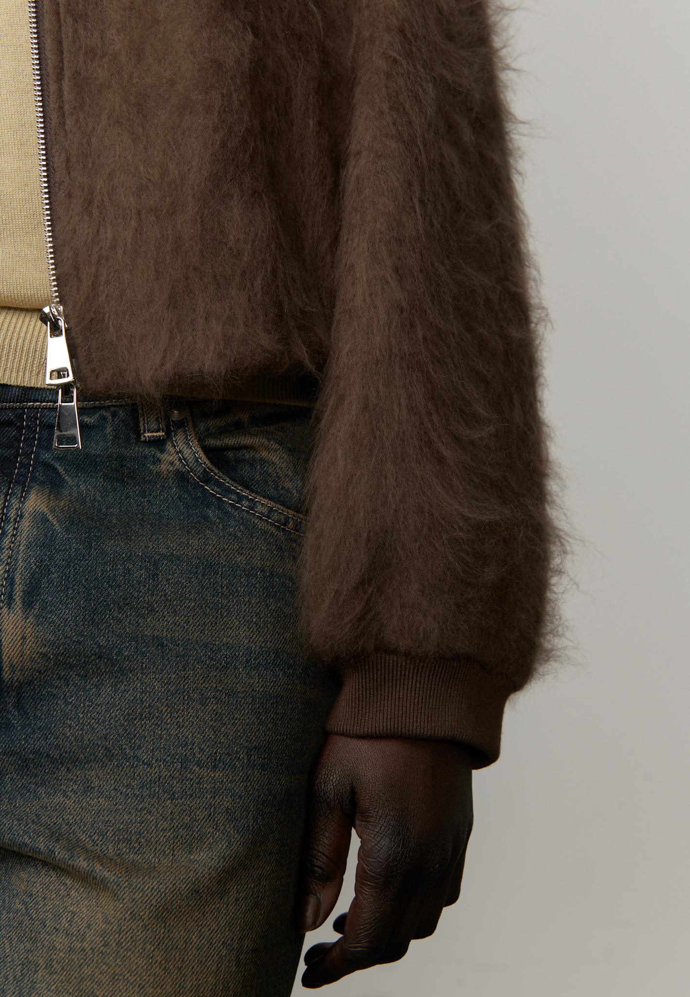 Brown fuzzy jacket worn over a beige garment with a neutral background
