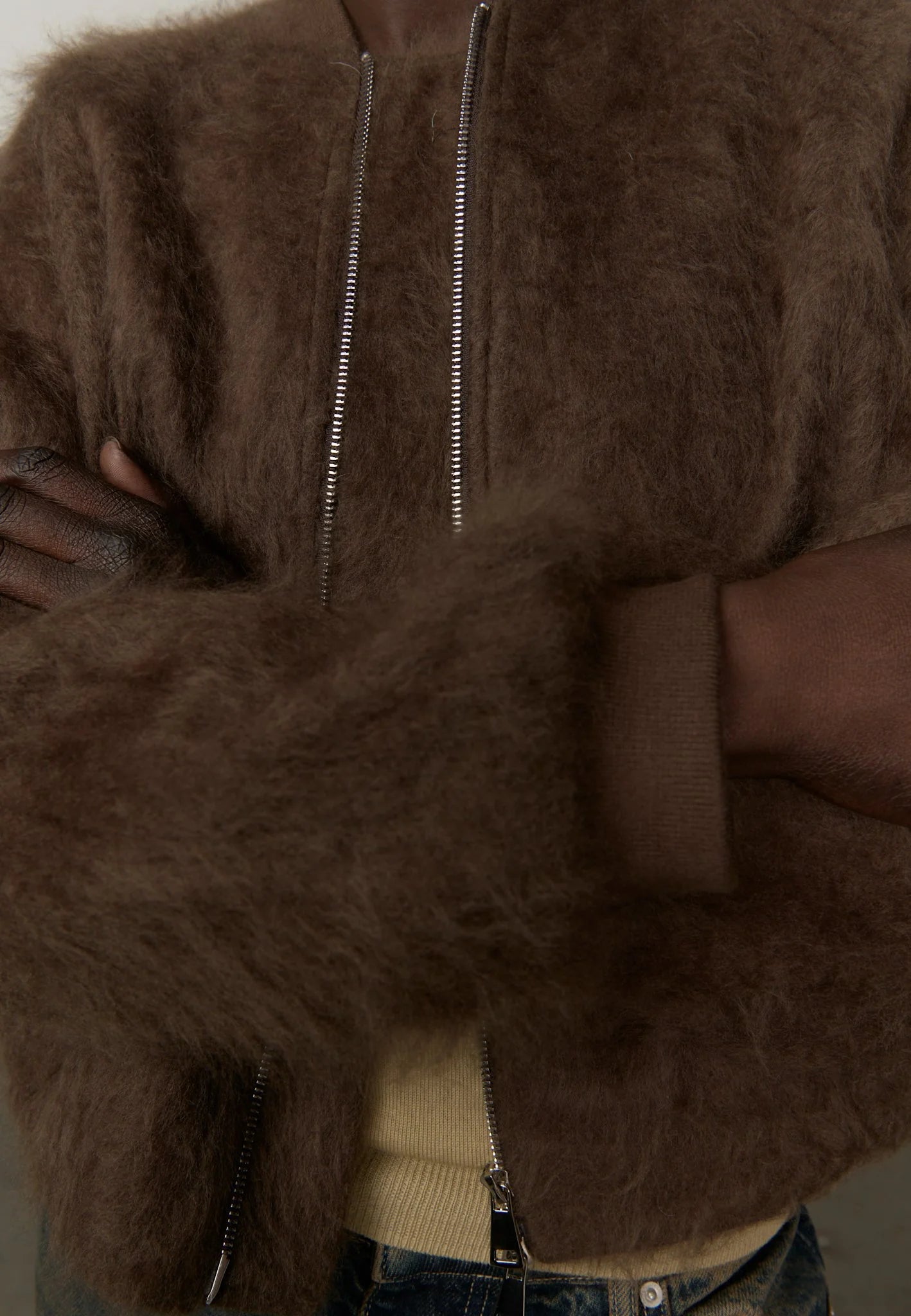 Brown fur jacket with a person wearing it, arms crossed.
